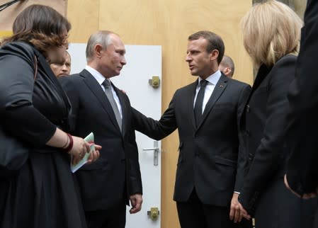 Russian President Vladimir Putin talks with French President Emmanuel Macron and his wife Brigitte Macron after the funeral of late French President Jacques Chirac during a national day of mourning in Paris