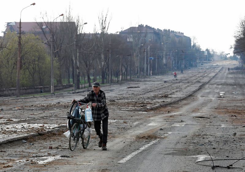 A local resident walks with a bicycle along a street in Mariupol