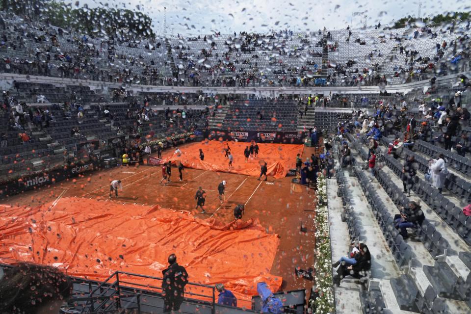 The rain cover is removed form the central court prior to the start of the final match between Denmark's Holger Rune and Russia's Daniil Medvedev at the Italian Open tennis tournament in Rome, Italy, Sunday, May 21, 2023. (AP Photo/Gregorio Borgia)