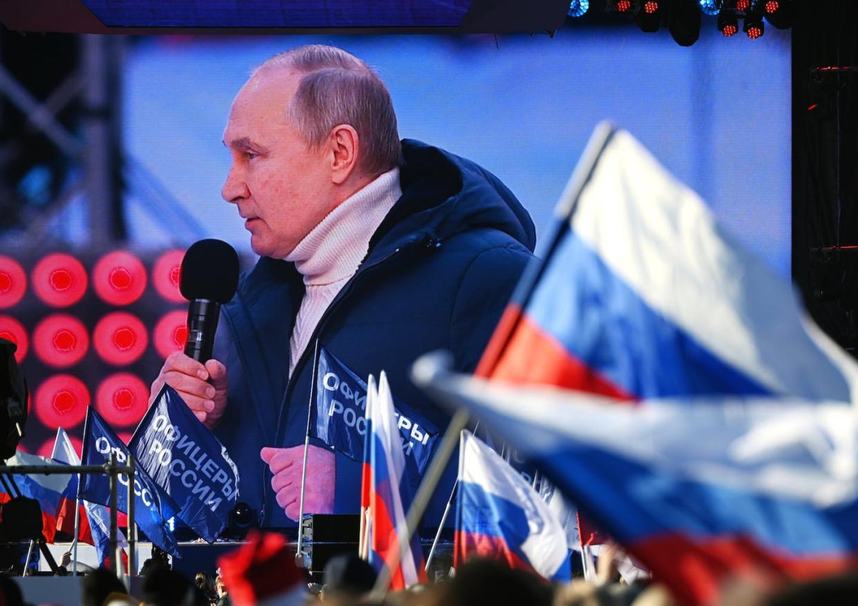 Vladimir Putin appears larger than life on screen as he addresses an audience at the Luzhniki Stadium in Moscow on the eighth anniversary of the annexation of Crimea in March 2022. (Vladimir Astapkovich/Sputnik Pool Photo via AP)