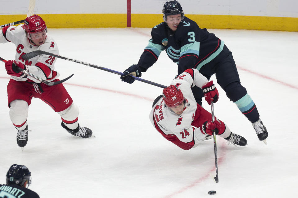 Carolina Hurricanes center Seth Jarvis (24) goes for the puck as Seattle Kraken defenseman Will Borgen (3) defends during the second period of an NHL hockey game Thursday, Oct. 19, 2023, in Seattle. (AP Photo/Jason Redmond)