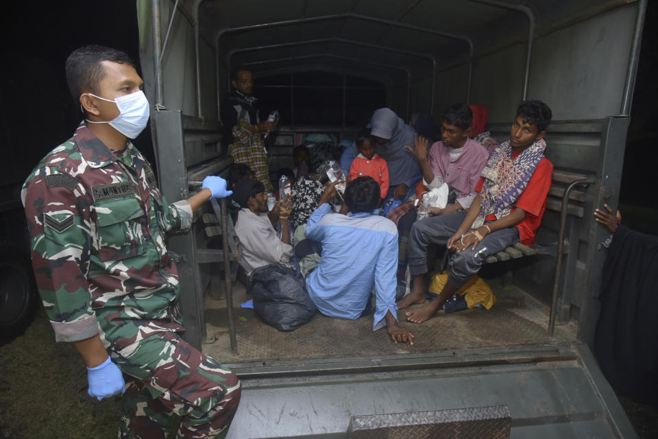 Ethnic Rohingya people sit at the back of a military truck upon arrival at a temporary shelter after their boat landed in Pidie, Aceh province, Indonesia, Monday, Dec. 26, 2022. A second group in two days of weak and exhausted Rohingya Muslims landed on a beach in Indonesia's northernmost province of Aceh on Monday after weeks at sea, officials said. (AP Photo/Rahmat Mirza)