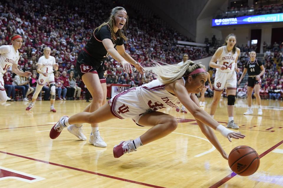 Indiana's Sydney Parrish (33) dives for a loose ball as Nebraska's Isabelle Bourne (34) watches during the first half of an NCAA college basketball game, Sunday, Jan. 1, 2023, in Bloomington, Ind. (AP Photo/Darron Cummings)