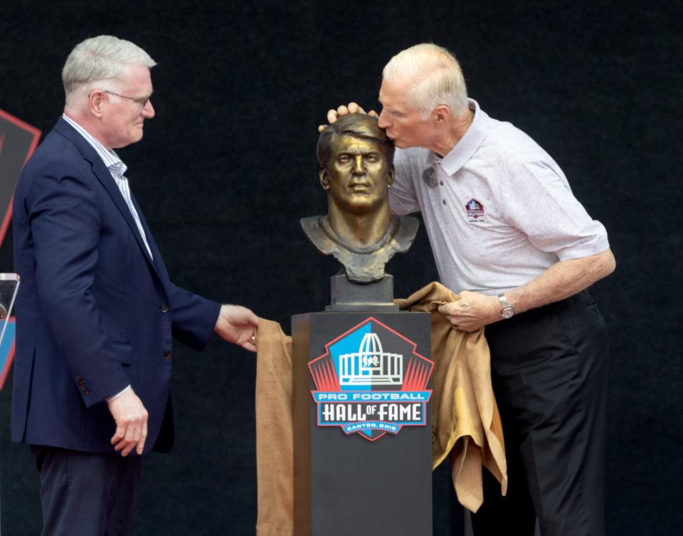 Chuck Howley’s son Scott watches presenter Bob Lilly kiss Chuck's bust during the Pro Football Hall of Fame Enshrinement on Saturday.