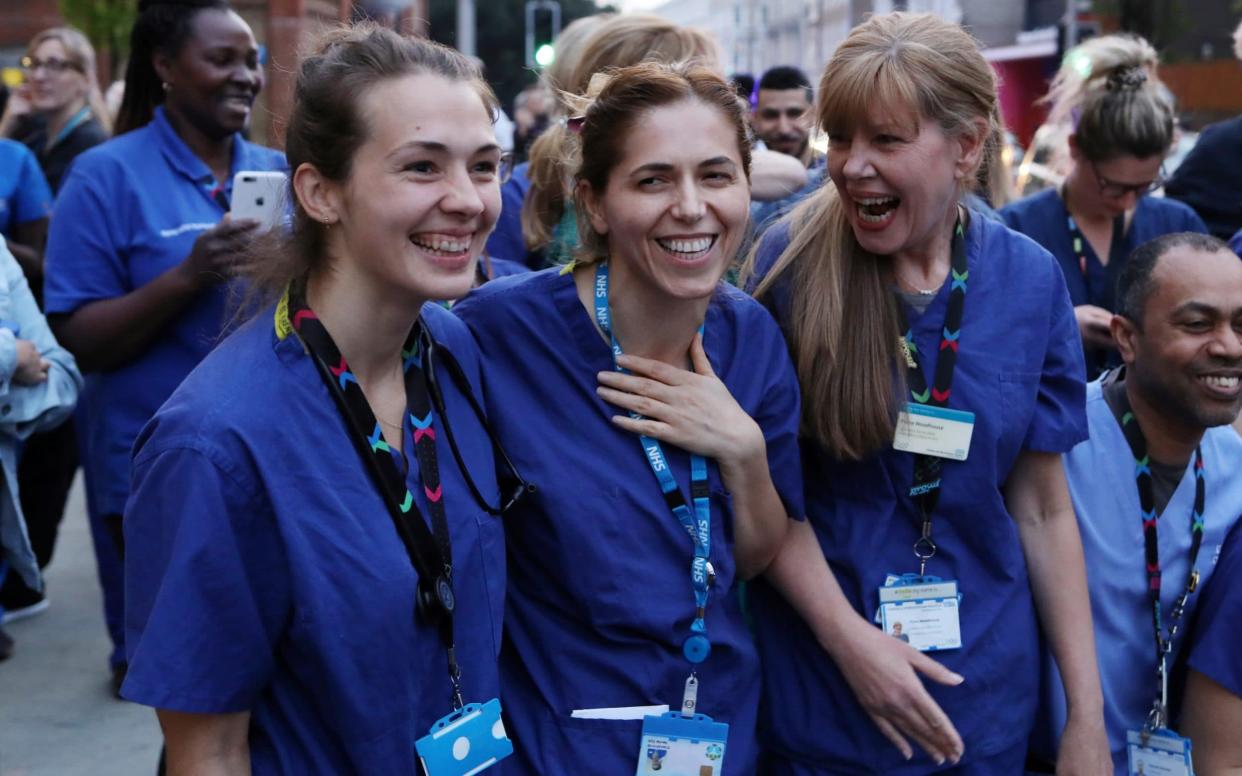 Three NHS workers outside Chelsea and Westminster Hospital during the Clap for our Carers campaign smiling and laughing - Kevin Coombs/Reuters