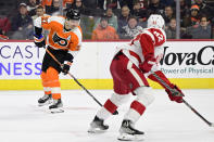 Philadelphia Flyers' Scott Laughton, left, takes a shot for a goal past the defense of Detroit Red Wings' Jordan Oesterle (82) during the second period of an NHL hockey game, Saturday, March 25, 2023, in Philadelphia. (AP Photo/Derik Hamilton)