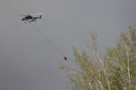 A helicopter flies into thick smoke while battling a major forest fire outside of Fort McMurray May 4, 2016. REUTERS/Topher Seguin