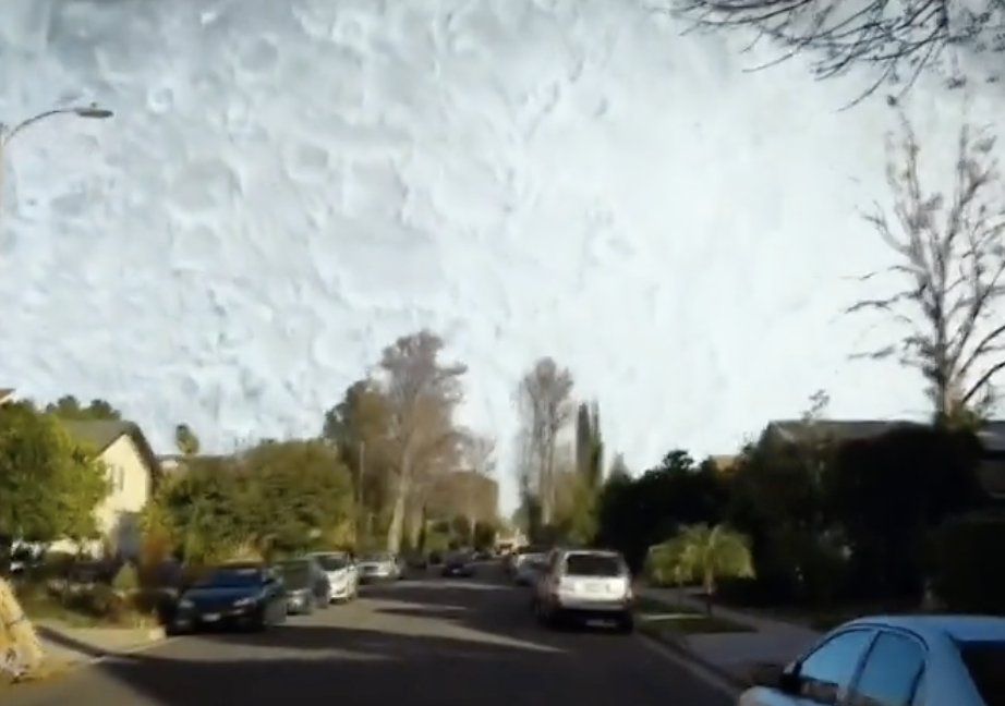 Close-up of a huge moon filling the daylight sky above a suburban street