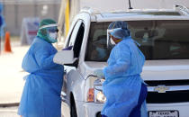 Medical personnel administer COVID-19 testing at a drive-through site, Friday, Aug. 14, 2020, in San Antonio. Coronavirus testing in Texas has dropped significantly, mirroring nationwide trends, just as schools reopen and football teams charge ahead with plans to play. (AP Photo/Eric Gay)