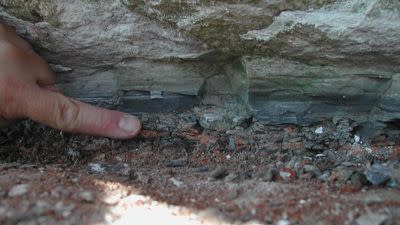 A hand points to a boundary point along rocks, indicated by a change in color, texture, and size