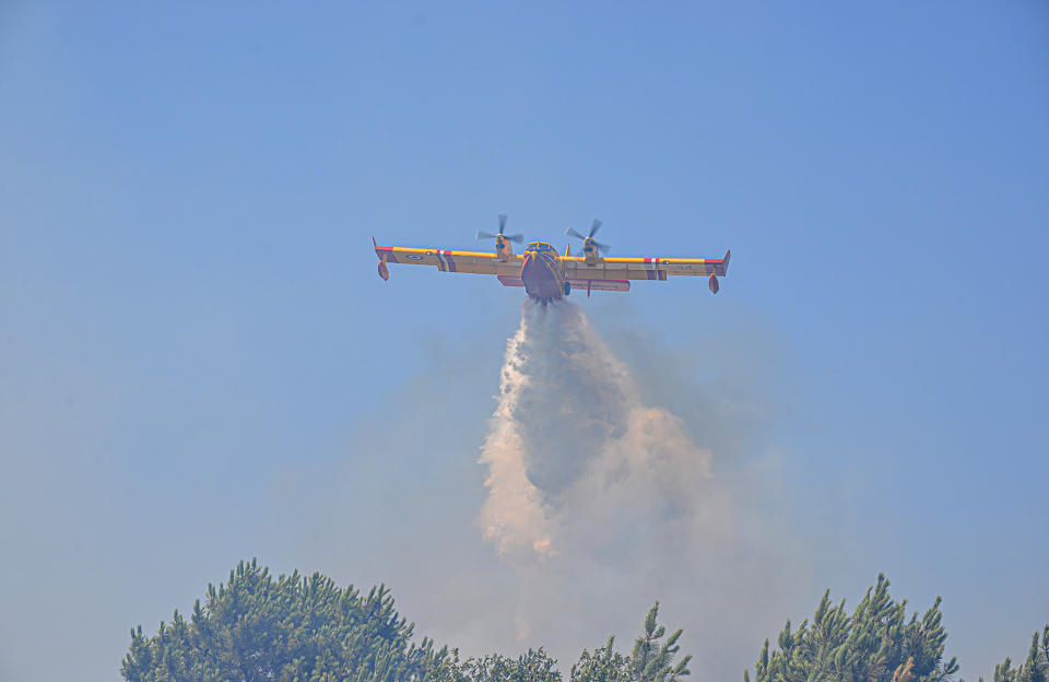 This photo provided by the fire brigade of the Gironde region (SDIS 33) shows a water-bombing plane spreads water La Teste-de-Buch, southwestern France, Tuesday, July 19, 2022. In the Gironde region of southwest France, two massive fires feeding on tinder-dry pine forests also have forced tens of thousands of people to flee homes and summer vacation spots since they broke out July 12. (SDIS 33 via AP)
