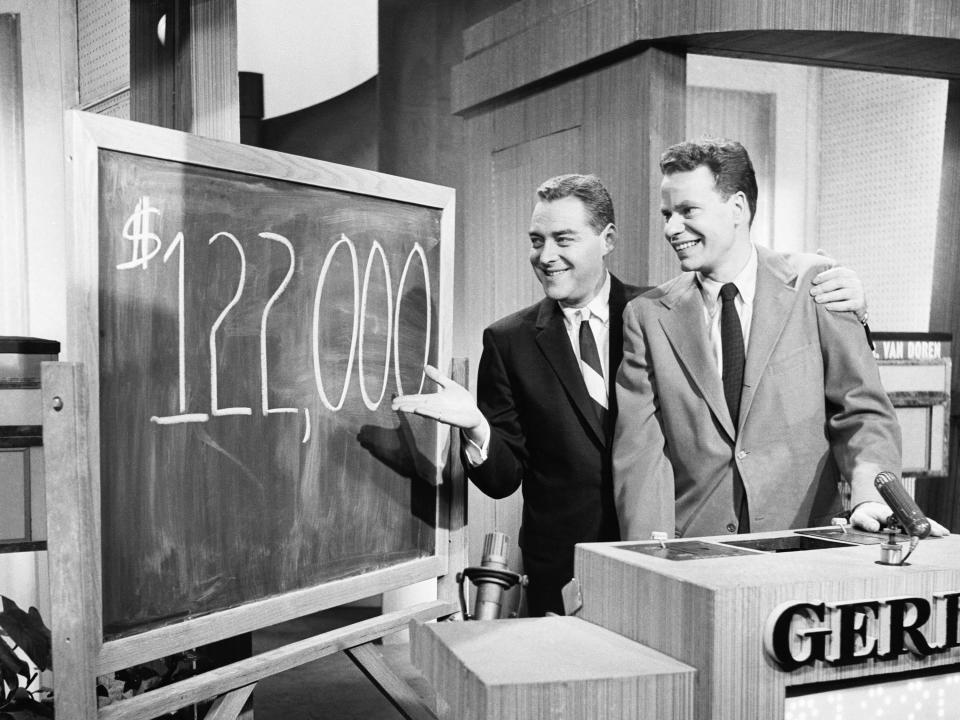 "Twenty One" host Jack Barry and contestant Charles Van Doren on set looking at chalkboard with $122,000 written on it