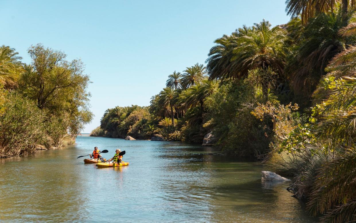 Friends kayaking together in a lake while on vacation in Crete.