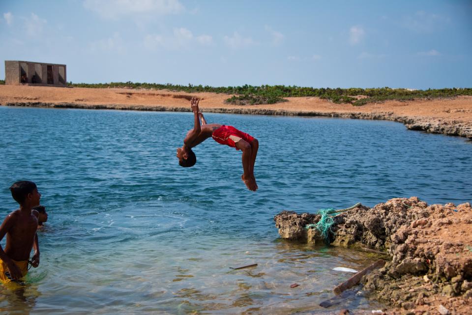 A local child dives into an impossibly deep watering hole believed to have been created by a meteorite (Valentina Morriconi)