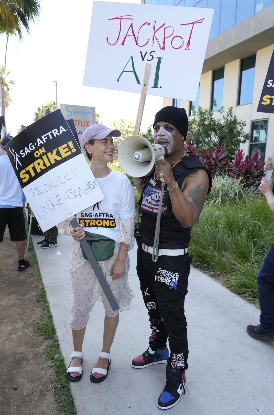 Actors Sarah Paulson, left, and Josiah Jackson, also known as Jackpot, walk on a picket line outside Netflix studios on Tuesday, July 25, 2023, in Los Angeles. The actors strike comes more than two months after screenwriters began striking in their bid to get better pay and working conditions. (AP Photo/Chris Pizzello)