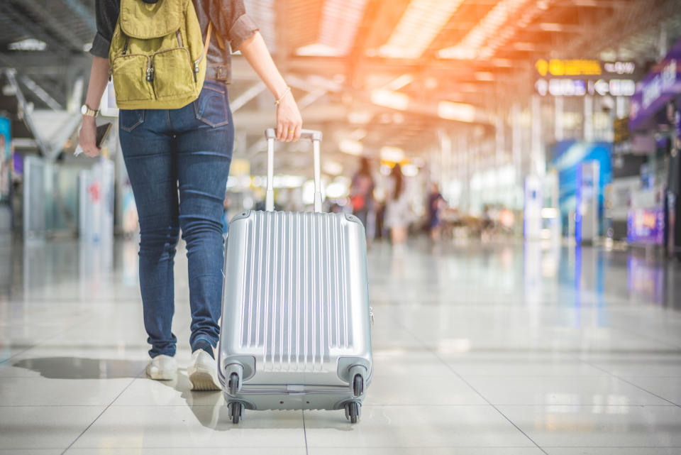 Beauty Asian woman traveling and holding suitcase in the airport. People and Lifestyles concept. Travel around the world theme. Back view and lower angle.