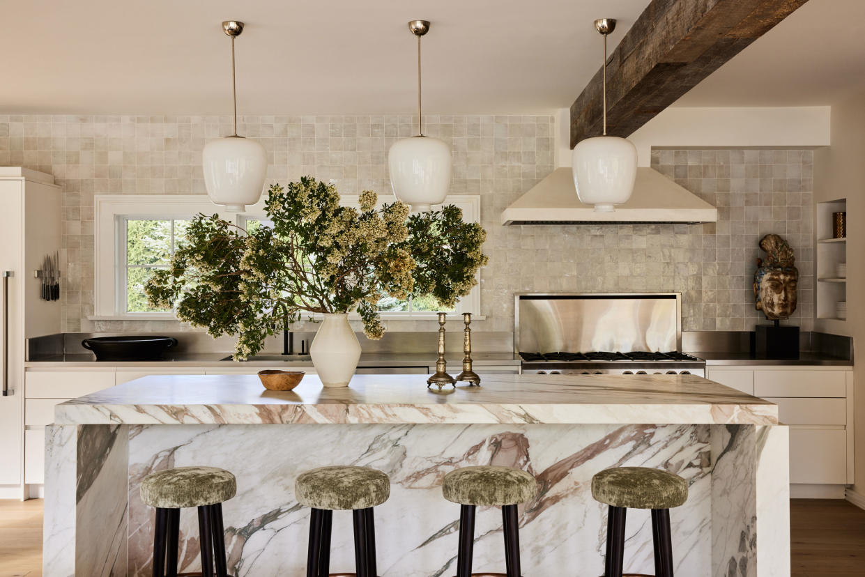  A kitchen with a marble island and zellige tile walls. 