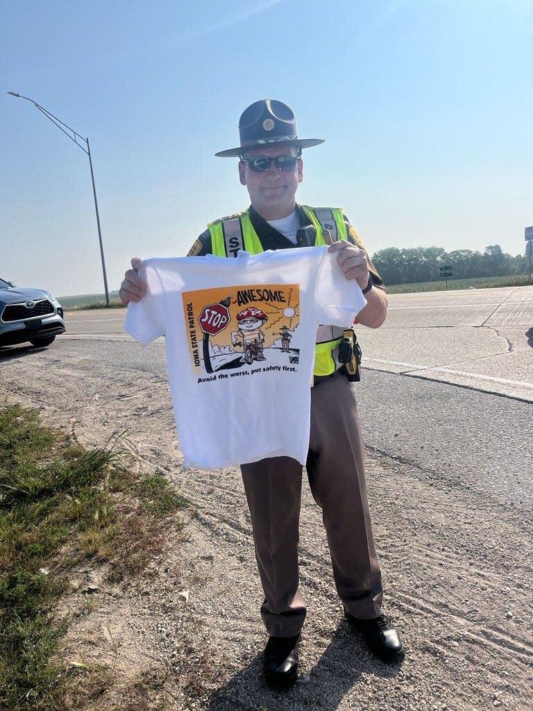 State Trooper Bob Conrad holds up a t-shirt before handing it to an 11-year-old boy who needed help finding a sag wagon during Monday's ride from Storm Lake to Carroll.