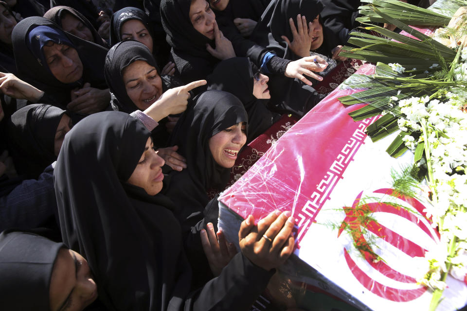 Mourners reach out to touch the caskets of those killed in a suicide car bombing that targeted members of Iran's powerful Revolutionary Guard in earlier in the week, killing at least 27 people, in Isfahan, Iran, Saturday, Feb. 16, 2019. The head of the Guard has threatened to retaliate against neighboring Saudi Arabia and United Arab Emirates over the bombing. (AP Photo/Ebrahim Noroozi)