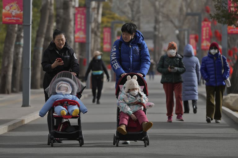 Dos mujeres pasean con niños por un parque en Pekín, China, el 19 de enero de 2023. 