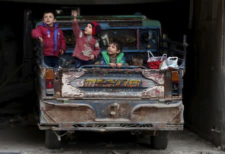 A boy gestures as he sits with others on a pick-up truck in the rebel held Douma neighborhood of Damascus, Syria March 2, 2016. REUTERS/Bassam Khabieh