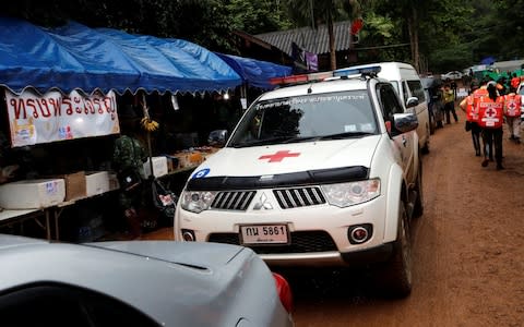 Ambulances wait outside the Tham Luang cave complex  - Credit: Reuters