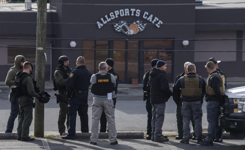 Police gather near a neighborhood business, Thursday, Nov. 14, 2019, while searching for a Marine deserter who is wanted for questioning in a murder case, in Roanoke, Va. (AP Photo/Don Petersen)