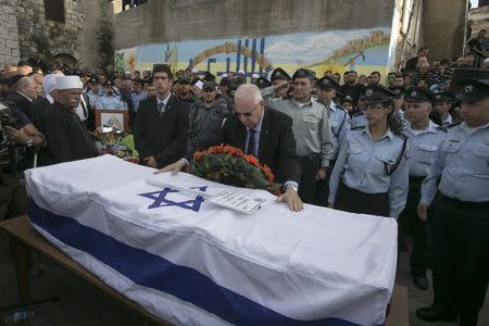 Israel's President Reuven Rivlin touches the flag draped coffin of Israeli Druze police officer Zidan Nahad Seif during his funeral in the northern village of Yanuh-Jat November 19, 2014. Two Palestinians armed with a meat cleaver and a gun killed four rabbis and the Druze police officer in a Jerusalem synagogue on Tuesday before being shot dead by police, the deadliest such incident in six years in the holy city. REUTERS/Baz Ratner (ISRAEL - Tags: POLITICS CIVIL UNREST)