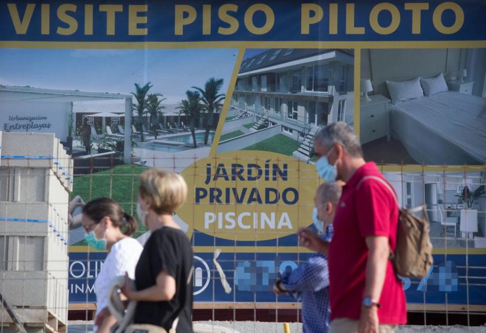 Un grupo de personas pasa frente al anuncio de unos apartamentos en A Mariña, Lugo, España, el 26 de julio de 2020.