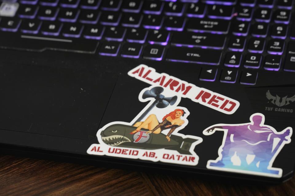 U.S. Air Force Airman Robert Linzy's laptop bears stickers at Al-Udeid Air Base, Qatar, Friday, Dec. 2, 2022. As over a million World Cup fans fill stadiums with cheers and carry heady optimism through the streets of Doha, some 8,000 American troops are running air wars in Afghanistan, Iraq, Syria and other hotspots in the Middle East mere miles away. (AP Photo/Jon Gambrell)