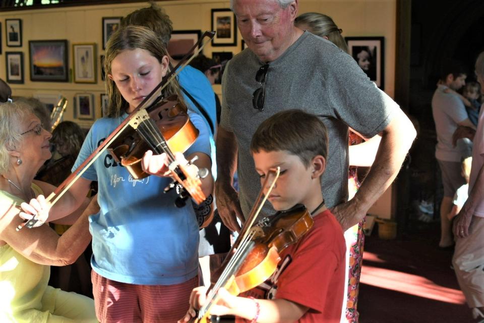 Eva Melin, 10, of Ponte Vedra Beach, Florida, and Luke Brymer, 8, of Oxford, learn to play the viola and violin at Hoover Auditorium in Lakeside as part of an “Instrument Petting Zoo.”
