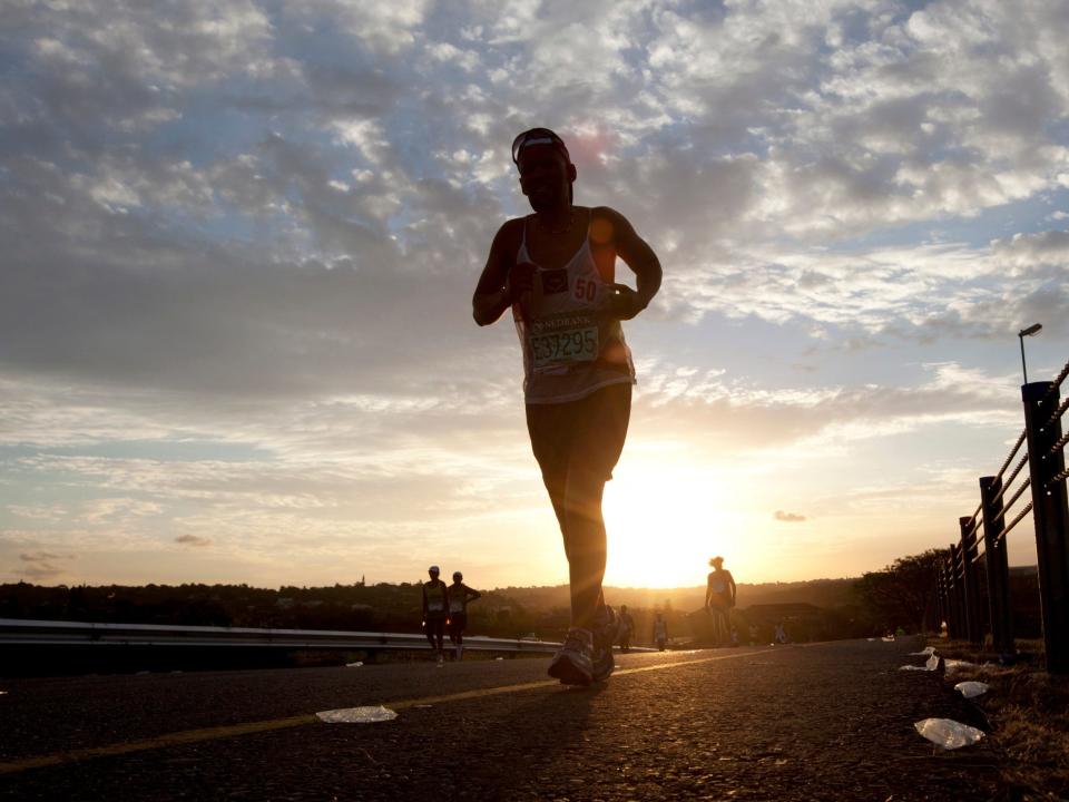 A runner is seen on a road as the sun sets