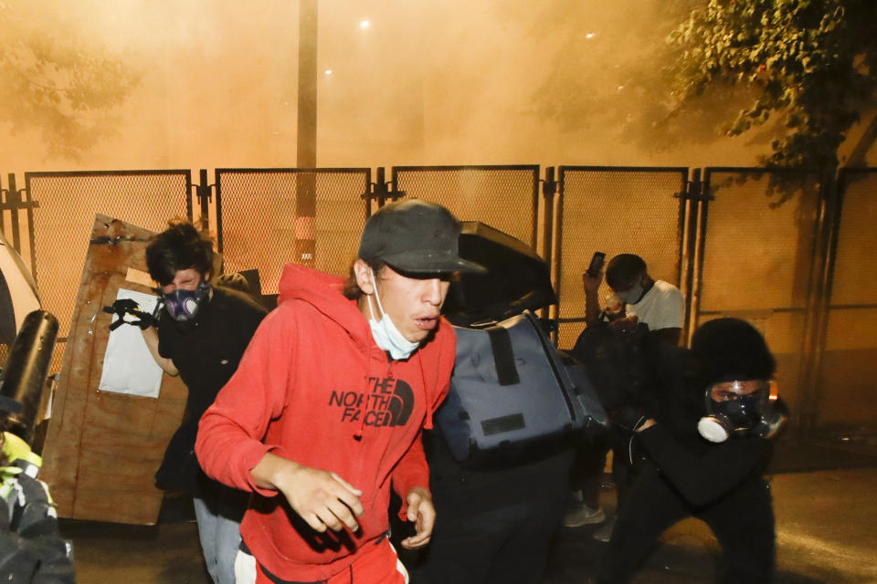 FILE - In this July 23, 2020, file photo, demonstrators back away from tear gas during a protest at the Mark O. Hatfield United States Courthouse in Portland, Ore. Federal agents have left Portland, but city officials are still learning about and cleaning tear gas residue that lingers in the streets, dirt and possibly storm drains that empty into the Willamette River. (AP Photo/Marcio Jose Sanchez, File)