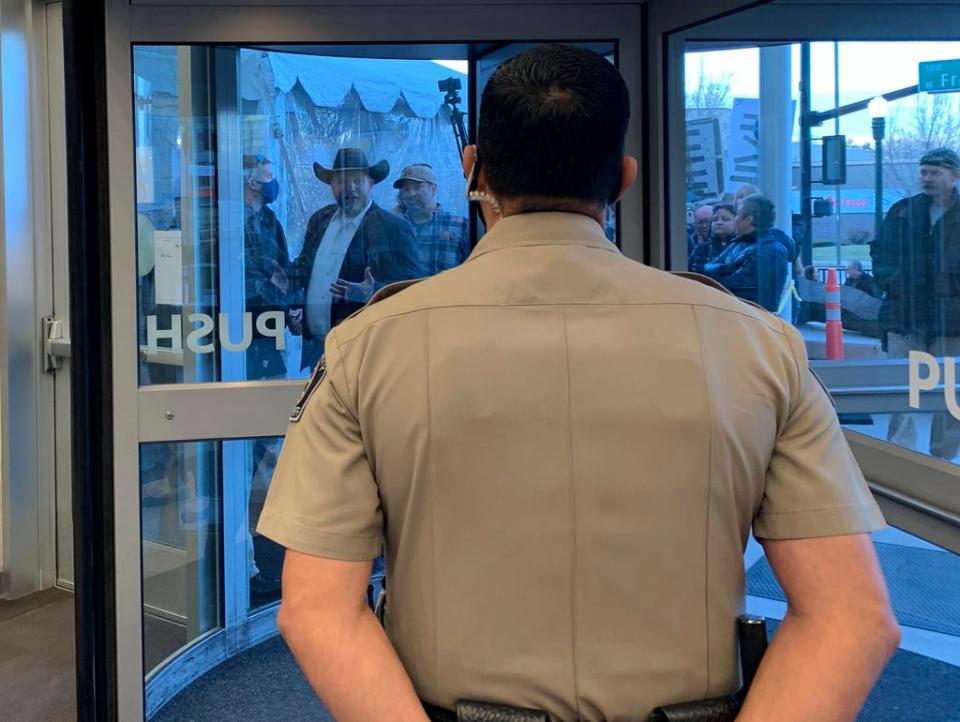 Anti-government activist Ammon Bundy, wearing a cowboy hat, yells through the closed Ada County Courthouse door at law enforcement officers inside Monday, March 15, 2021, in Boise, Idaho.