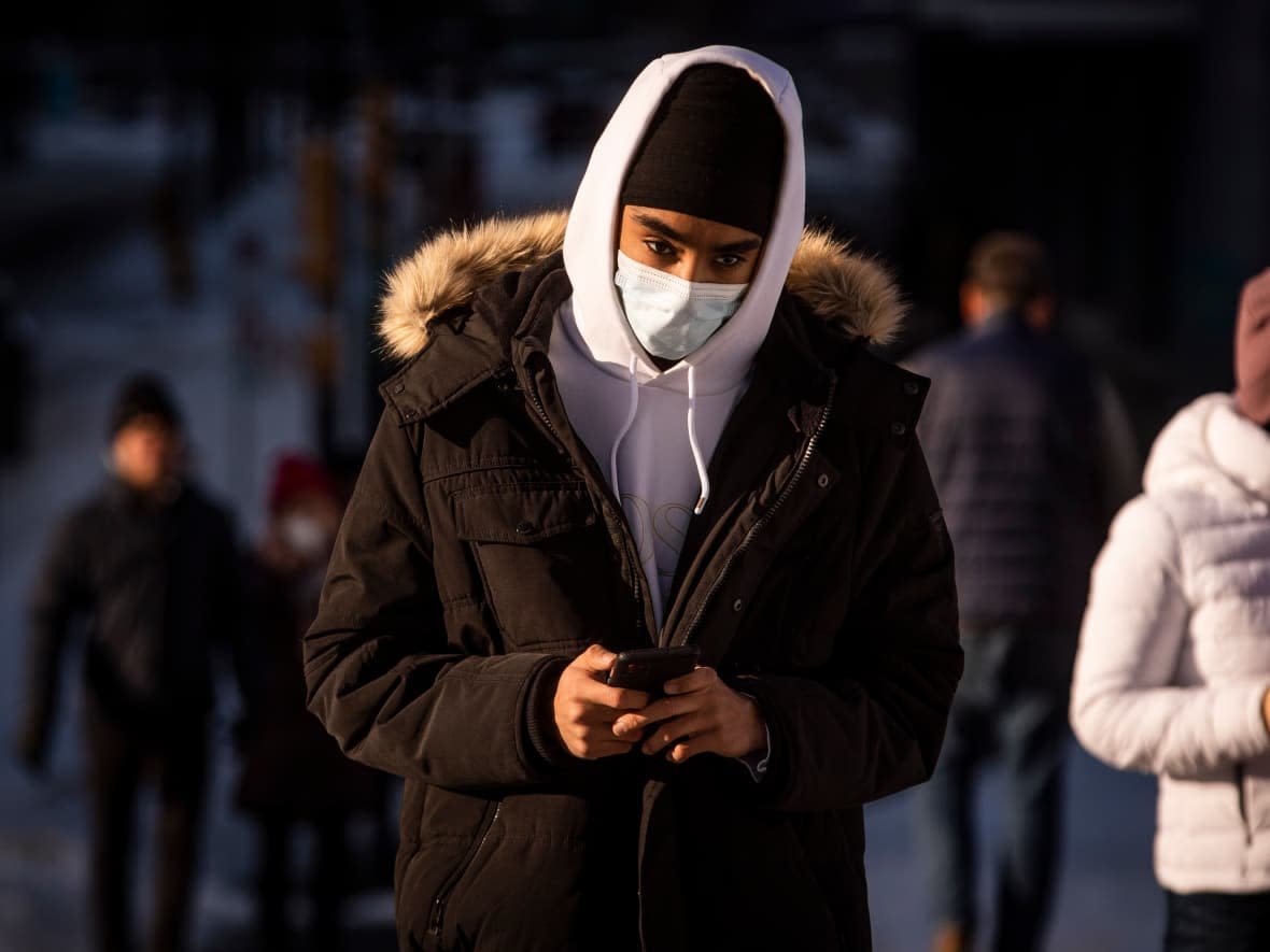 A pedestrian wears a face mask to protect against COVID-19 while walking in downtown Vancouver on Dec. 30, 2021. (Ben Nelms/CBC - image credit)