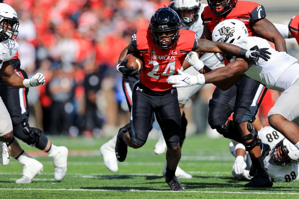 FILE - Cincinnati running back Jerome Ford (24) carries the ball as he breaks a tackle against UCF linebacker Jeremiah Jean-Baptiste, right, during the first half of an NCAA college football game, Saturday, Oct. 16, 2021, in Cincinnati. For Cincinnati (13-0), a member of the second-tier American Athletic Conference, the planets aligned. The Bearcats landed as the No. 4 seed in the CFP, invading the domain of college football's blue bloods. (AP Photo/Aaron Doster, File)