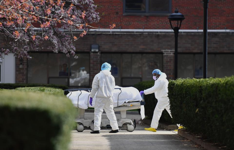 Medical personnel wearing personal protective equipment transport the body of a deceased patient from a refrigerated truck to Kingsbrook Jewish Medical Center on April 8, 2020 in Brooklyn, New York.