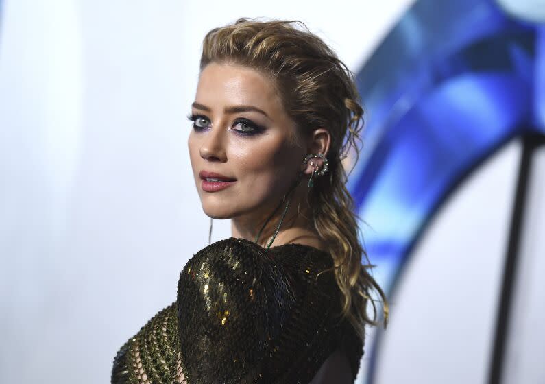 Amber Heard poses in a gold, sparkly dress.