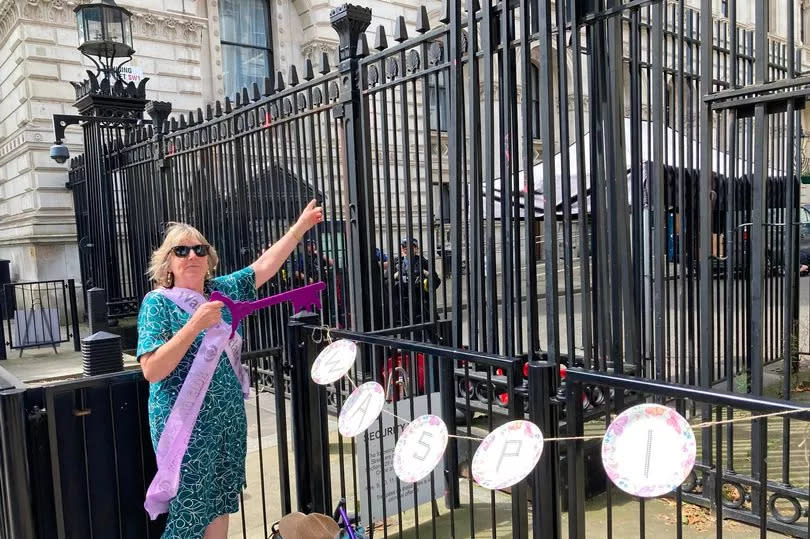 Elaine and Kathleen at the gates of Downing Street hanging up WASPI-related material