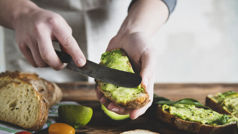 hands spreading avocado 