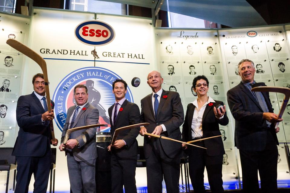 2017 Hockey Hall of Fame inductees, from left, Teemu Selanne, Mark Recchi, Paul Kariya, Jeremy Jacobs, Danielle Goyette and Dave Andreychuk put pucks in the air during a new conference in Toronto, Friday, Nov. 10, 2017. (Christopher Katsarov/The Canadian Press via AP)