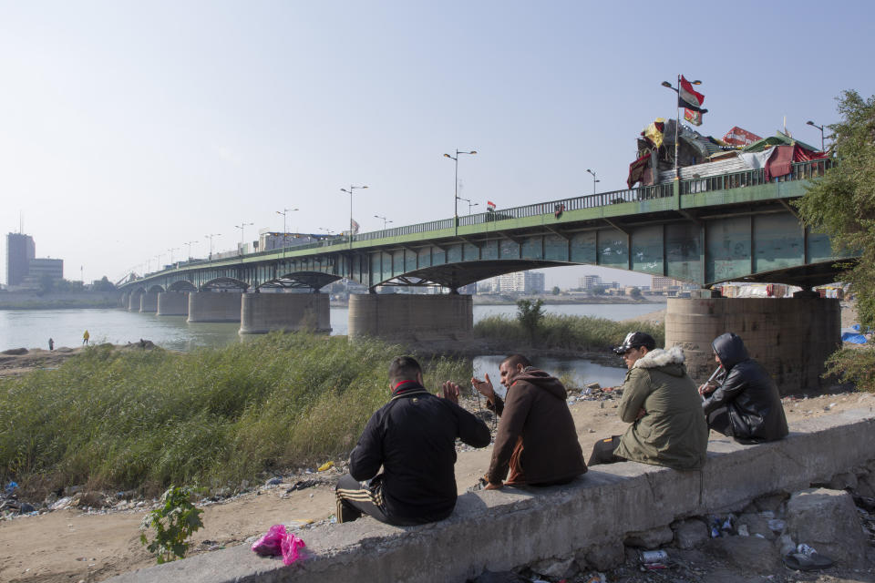 Anti-government protesters camp behind cement blocks, on the right side of a bridge, that separate them from riot police, on the left side, during the ongoing protests in Tahrir Square, Baghdad, Iraq, Thursday, Dec. 26, 2019. (AP Photo/Nasser Nasser)