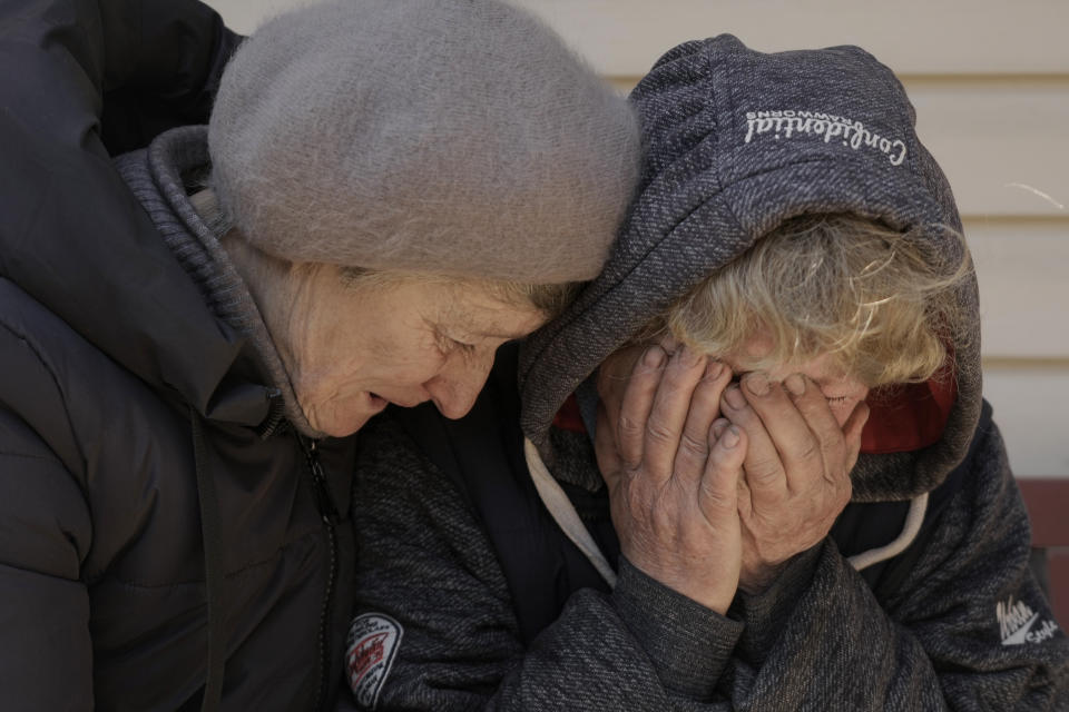 FILE - A neighbor comforts Natalya, whose husband and nephew were killed by Russian forces, as she cries in her garden in Bucha, Ukraine, April 4, 2022. The scenes that emerged from this town near Kyiv a year ago after it was retaken from Russian forces have indelibly linked its name to the savagery of war. Bodies of civilians lay where they had fallen, more bodies were found inside homes, others were unearthed from a mass grave. (AP Photo/Vadim Ghirda, File)