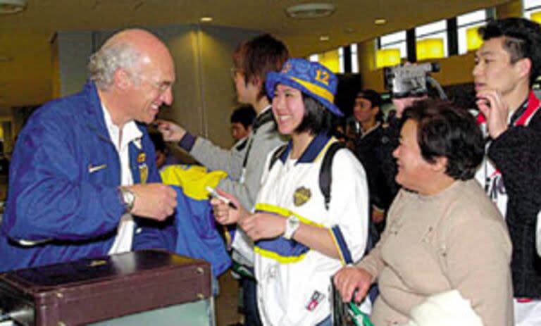 En el aeropuerto de Tokio, Carlos Bianchi le firma un autógrafo a una japonesa fanática de Boca; el plantel ya vive la gran final frente a Real Madrid
