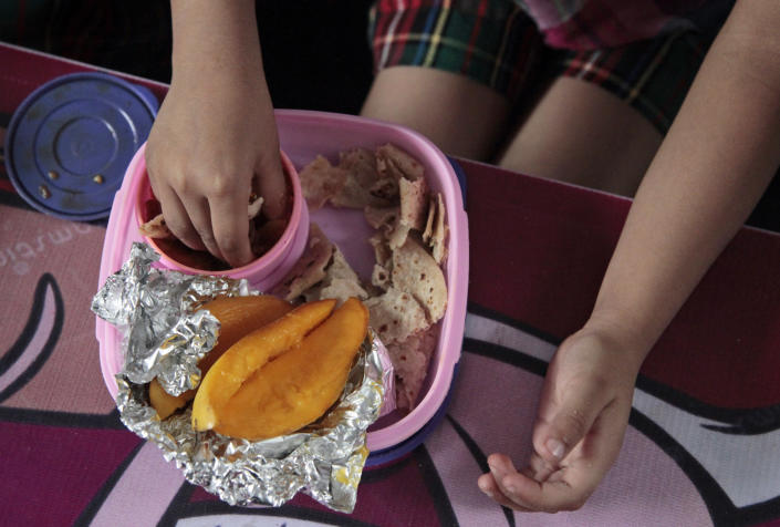 Baani, a 5-year-old Indian schoolgirl, eats her lunch prepared by her mother, consisting of flatbread, a turnip dish and mangoes, at a school in Jammu, India, Tuesday, May 6, 2014. Most countries seem to put a premium on feeding school children a healthy meal at lunchtime. U.S. first lady Michelle Obama is on a mission to make American school lunches healthier too, by replacing greasy pizza and french fries with whole grains, low fat protein, fresh fruit and vegetables. (AP Photo/Channi Anand)