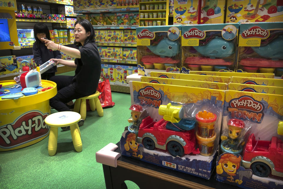 A woman and child play at a display for Play-Doh toys made by American toymaker Hasbro at a toy store in Beijing, Wednesday, May 15, 2019. For many Americans, President Donald Trump's trade war may soon get very real. His administration is preparing to extend 25% tariffs to practically all Chinese imports not already hit with duties, including toys, sneakers, shirts, alarm clocks, toasters and coffeemakers. (AP Photo/Mark Schiefelbein)