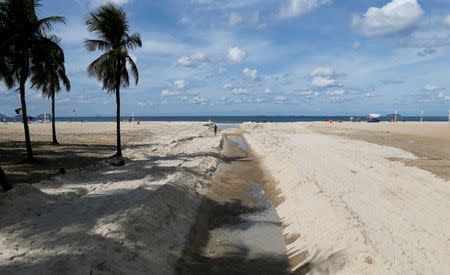 A man runs next to sewage system flowing on Copacabana beach in Rio de Janeiro, Brazil, June 9, 2016. REUTERS/Sergio Moraes