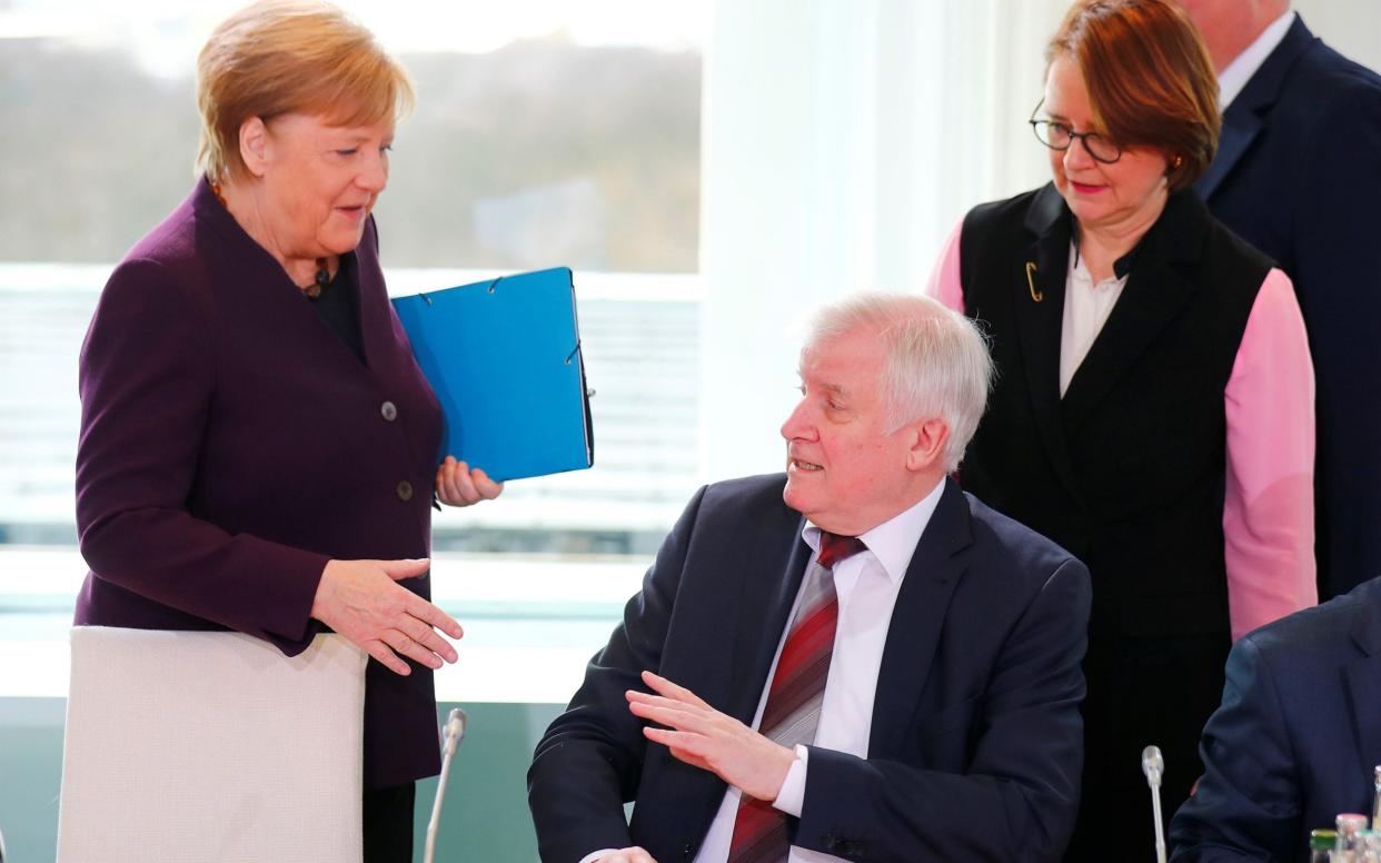 German Interior Minister Horst Seehofer refuses to shake the hand of German Chancellor Angela Merkel -  HANNIBAL HANSCHKE/REUTERS