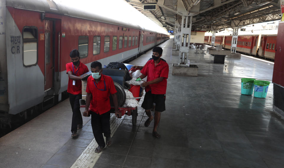 Railway workers wearing masks push a handcart at Lokmanya Tilak Terminus in Mumbai, India, Monday, March. 23, 2020. As India expanded its virus-containment measures and halted its lifeblood train network, the federal government warned Monday of strict legal action for those who flout the rules. (AP Photo/Rafiq Maqbool)