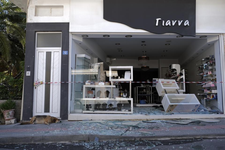 A dog lies next to a damaged shop after a strong earthquake in Arkalochori village on the southern island of Crete, Greece, Monday, Sept. 27, 2021. A strong earthquake struck the Greek island of Crete and killed one person and injured several more. Home and churches were damaged and rock slides occurred near the country's fourth-largest city.(AP Photo/Harry Nakos)